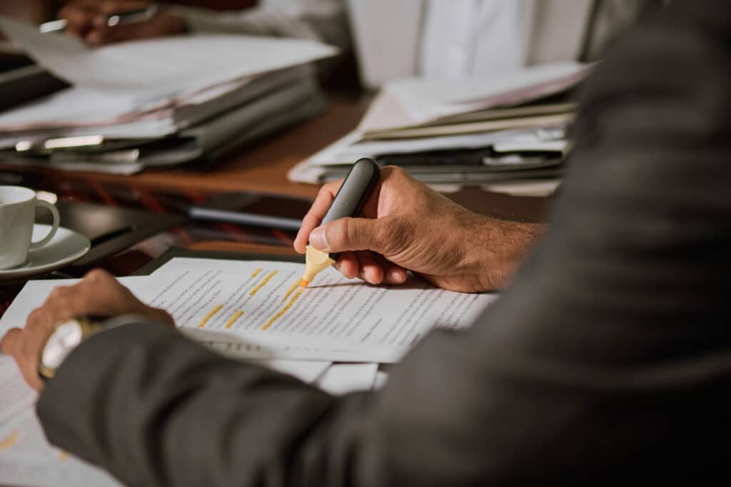 Focus on hand of experienced male lawyer or director of company underlining some lines of contract text with highlighter